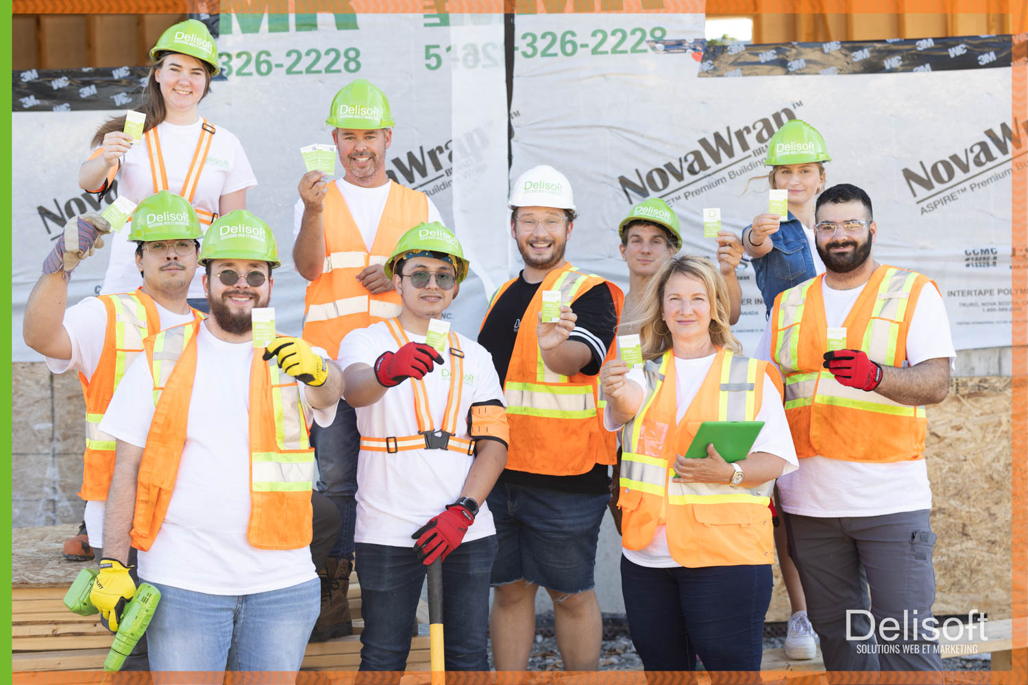 Équipe de Delisoft en tenue de construction, portant des casques verts et des gilets de sécurité orange, tenant des cartes de visite devant un chantier de construction.